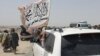 PAKISTAN - People wave a Taliban flag as they drive through the Pakistani border town of Chaman on July 14, 2021, after the Taliban claimed they had captured the Afghan side of the border crossing of Spin Boldak along the frontier with Pakistan